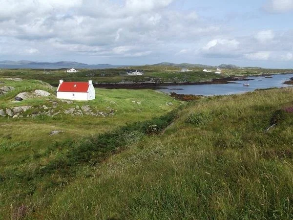 No. 1 Ardveenish holiday cottage on the Isle of Barra, Scotland — a traditional white croft house with red roof set against Hebridean landscape and bay