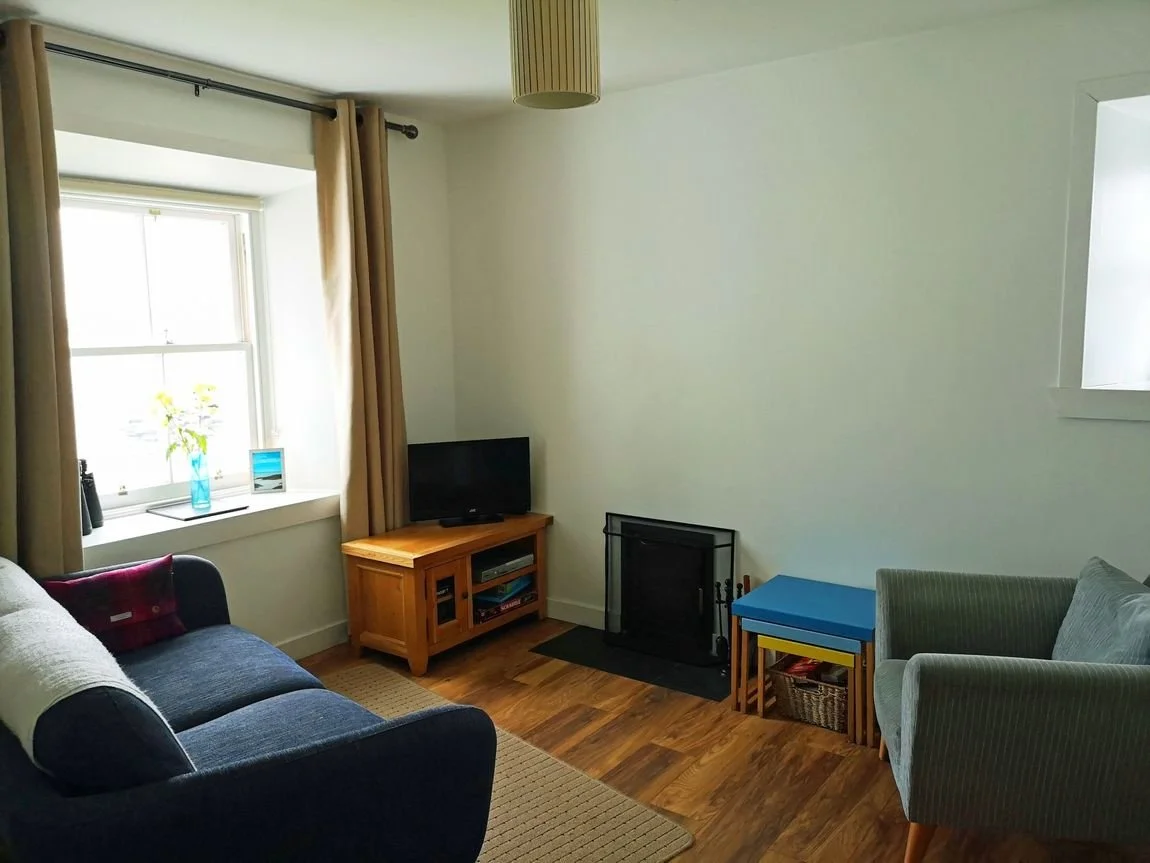 Comfortable sitting room at No. 1 Ardveenish with sofa, fireplace and sea-view window