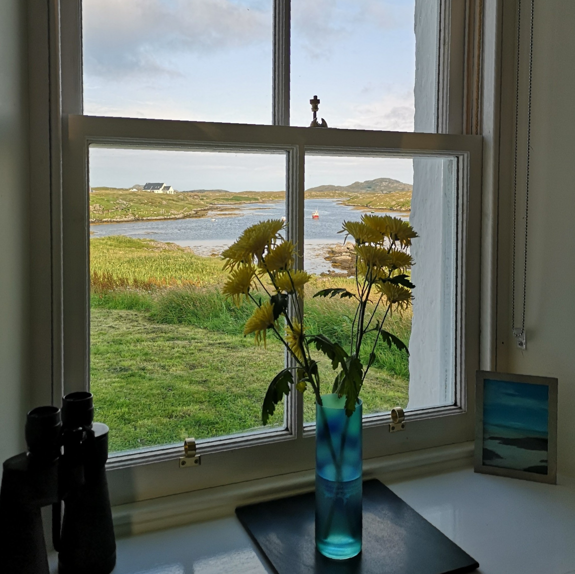 View from the window of No. 1 Ardveenish — flowers on the sill, loch and hills of Barra beyond