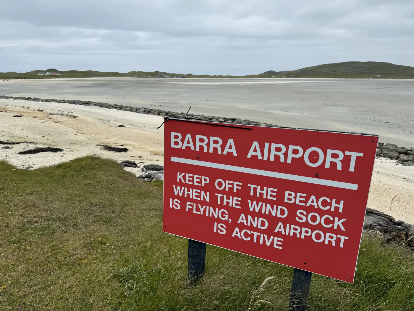 The iconic red Barra Airport sign at Traigh Mhòr — the world's only commercial beach airport on the Isle of Barra